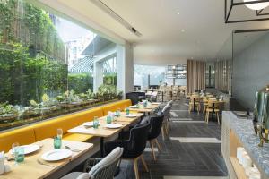 ein Restaurant mit Holztischen und -stühlen und großen Fenstern in der Unterkunft JonoX Phuket Karon Hotel in Karon Beach