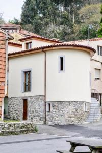 a white building with a red roof and a bench at APARTAMENTOS RURALES El Llagar de Cue in Llanes