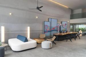 ein Wohnzimmer mit einer weißen Couch und einem Klavier in der Unterkunft JonoX Phuket Karon Hotel in Karon Beach