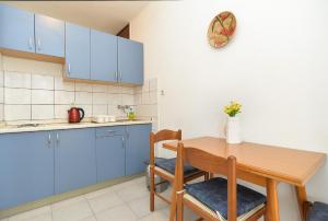 Apartments Plominska 938 في راباك: مطبخ مع دواليب زرقاء وطاولة خشبية