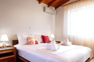 una camera da letto con un grande letto bianco con asciugamani di Villa Luz a Koumariés