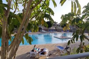 un gruppo di persone sdraiate su sedie a bordo piscina di Casa de Playa Sol Y Mar a El Médano