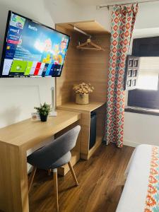 a room with a desk and a tv on a wall at Hotel QB Almagro Centro in Almagro