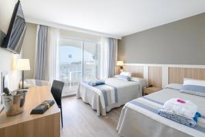 a hotel room with two beds and a desk at Gran Hotel Las Fuentes de Fantasía Hoteles in Alcossebre