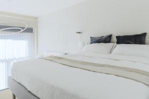 a white bed in a white bedroom with a window at Touch&Go - via Gaetano Previati 38, Milano in Milan