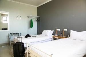 a room with two beds and a suitcase in it at Zzzone Boutique Hostel in Hermanus