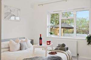 um quarto branco com uma cama branca e uma janela em LiveStay-Stylish Two Bed House with Private Garden em Londres