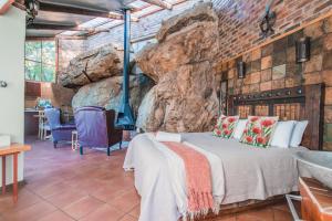 a bedroom with a bed and a rock wall at Thabela Thabeng in Parys