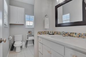 Un baño con inodoro, lavabo y espejo. en Nauti Beach, en Port Aransas