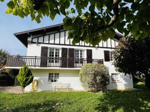 Biały dom z ławką przed nim w obiekcie Maison T4 à Cambo-les-Bains: 5 couchages, jardin arboré, balcon, cheminée, animaux acceptés, Wi-Fi fibre - FR-1-495-114 w mieście Cambo-les-Bains