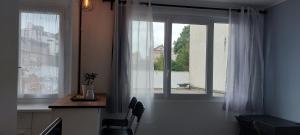 拉加恩–科隆的住宿－Cosy studio proche de la Défense Arena，厨房配有桌子和带白色窗帘的窗户。