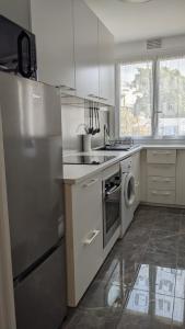 a kitchen with a stainless steel refrigerator and a dishwasher at Cosy studio proche de la Défense Arena in La Garenne-Colombes
