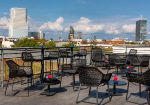 فندق سانا برلين في برلين: مجموعة من الكراسي والطاولات على شرفة مع أفق المدينة
