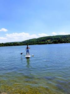 Ein Mann, der ein Paddelbrett auf einem See reitet in der Unterkunft Belle demeure Normande dans son écrin de verdure. in Manneville-sur-Risle