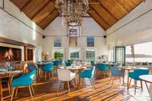 a dining room with tables and chairs and a chandelier at Adventure Pad's by The Farmhouse Hotel in Langebaan
