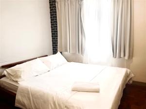 a bedroom with a white bed with a window at Selesa hill homestay in Bentong