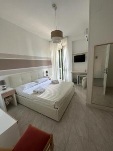 a white bedroom with a large bed and a mirror at Porto Cesareo Hotel in Porto Cesareo