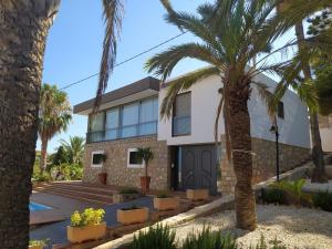 una casa con palme di fronte di Nuza, Villa con Piscina y Barbacoa a El Campello