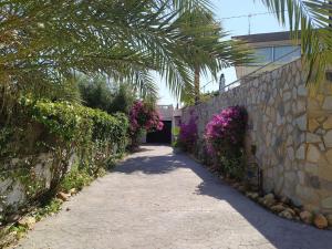 un sentiero con un muro di pietra e fiori viola di Nuza, Villa con Piscina y Barbacoa a El Campello