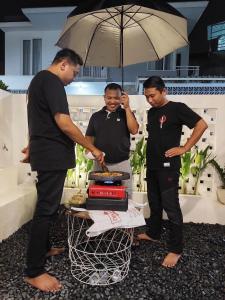 un grupo de tres hombres parados alrededor de una mesa con un pastel en Villa Tiga Dara Batu en Batu
