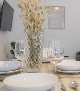 a vase with flowers in it sitting on a table with glasses at Azvalia - Larga 112 in El Puerto de Santa María