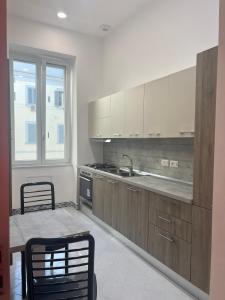 uma cozinha com armários de madeira, uma mesa e uma janela em Hotel Ausonia em Nápoles