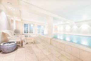 a swimming pool with a tub in a room with a table and chairs at Hotel Parkresidenz Christian VIII in Archsum