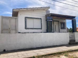 una pequeña casa blanca detrás de una pared de hormigón en LEG II en Monte Hermoso