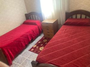 2 camas en un dormitorio con sábanas rojas y tocador en LEG II en Monte Hermoso