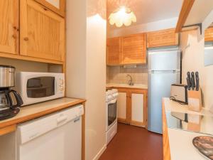 a kitchen with white appliances and wooden cabinets at Appartement lumineux 2 pièces, 6 couchages, proche pistes et commerces, avec parking et balcon - FR-1-330F-114 in Serre Chevalier