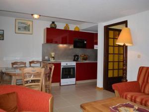 ein Wohnzimmer und eine Küche mit roten Schränken und einem Tisch in der Unterkunft Appartement Le Grand-Bornand, 5 pièces, 8 personnes - FR-1-241-197 in Le Grand-Bornand