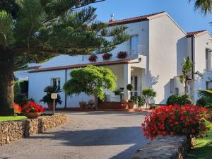 a white house with flowers in front of it at Arenosu Comfort Country Guesthouse in Fertilia
