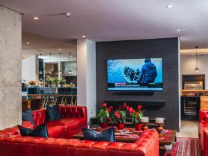 a living room with red couches and a tv on a wall at Boutique Ocean Views - incorporating Wendy's in Hermanus