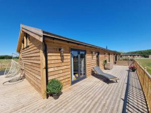 a wooden cabin with a bench on a deck at 4Bed Lodge Sleeps8-Pet Friendly-Hot Tub-Log Burner in York