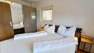 a bedroom with two beds with white pillows at MONA aus KMB Seeappartement direkt am Ossiacher See mit Hallenbad Terasse Skiarena Gerlitzen in Bodensdorf