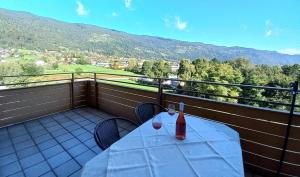 a table with a bottle and two glasses on a balcony at MONA aus KMB Seeappartement direkt am Ossiacher See mit Hallenbad Terasse Skiarena Gerlitzen in Bodensdorf