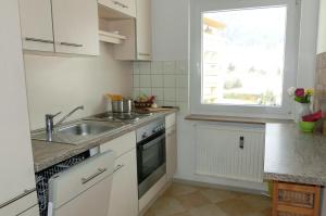 een keuken met witte kasten, een wastafel en een raam bij MONA aus KMB Seeappartement direkt am Ossiacher See mit Hallenbad Terasse Skiarena Gerlitzen in Bodensdorf