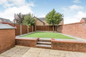 a garden with a brick fence and a grassy yard at SPACIOUS DETACHED 5 Bedroom4 Bathroom WIFI Parking in Newcastle under Lyme