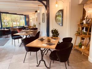 Le Clos Du Pontic Logis et Cit'Hotel في لانديرنو: مطعم بطاولات خشبية وكراسي سوداء