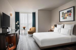 um quarto de hotel com uma cama branca e uma cadeira em Glens Palas Istanbul em Istambul