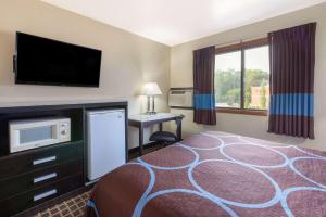 エルクハートにあるSuper 8 by Wyndham Elkhartのベッド1台、薄型テレビが備わるホテルルームです。
