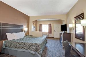 a hotel room with a bed and a flat screen tv at Days Inn & Suites by Wyndham Houston North - Spring in Westfield