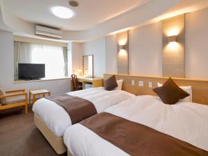 a hotel room with two beds and a television at Hotel Palm Spring in Iwaki
