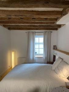 a bedroom with a large white bed with a window at La petite maison de Savennières in Savennières