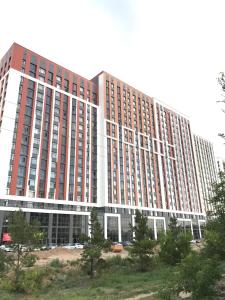 TaldykolʼにあるApartments ЖК АLAUの目の前に木々が植えられた大きな赤と白の建物