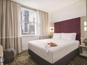 una habitación de hotel con una cama con un plato de comida. en Rendezvous Hotel Melbourne en Melbourne