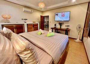 a bedroom with two beds and a flat screen tv at Three rare & private front beach villas in Thongsala