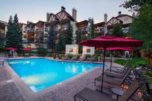 a pool at a hotel with chairs and an umbrella at Montaneros in Vail in Vail