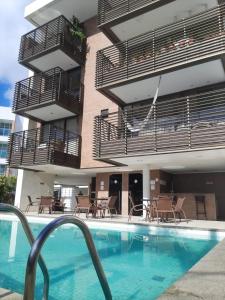 a hotel with a swimming pool in front of a building at Luxor Cabo Branco - João Pessoa PB in João Pessoa