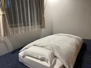 a bedroom with a bed with white sheets and a window at ＡkＢ63 in Sapporo +2 photos